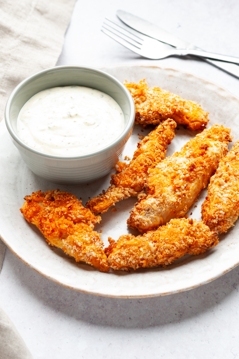 Air fried buffalo chicken tenders on a plate with ranch in a small bowl. 
