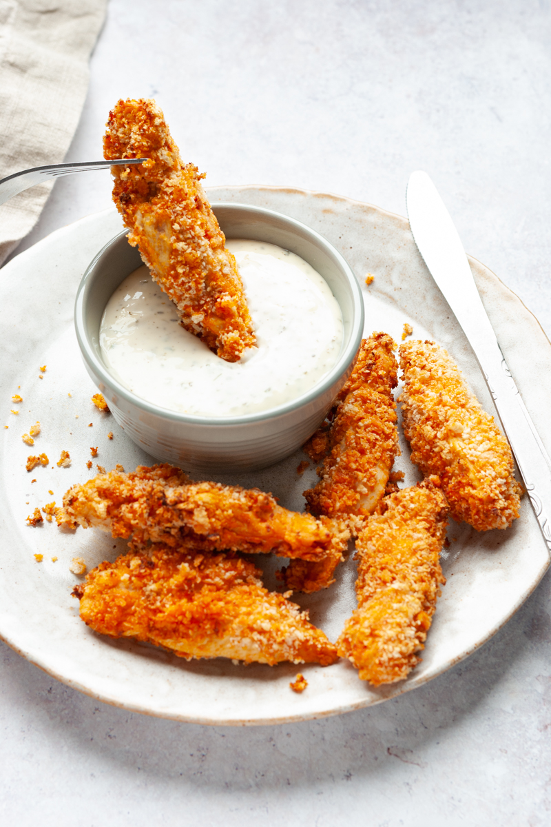 Air fried buffalo chicken tenders on a plate with ranch in a small bowl. 