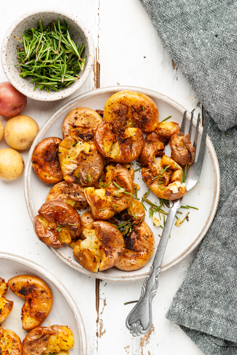 Smashed potatoes in a plate with a fork.