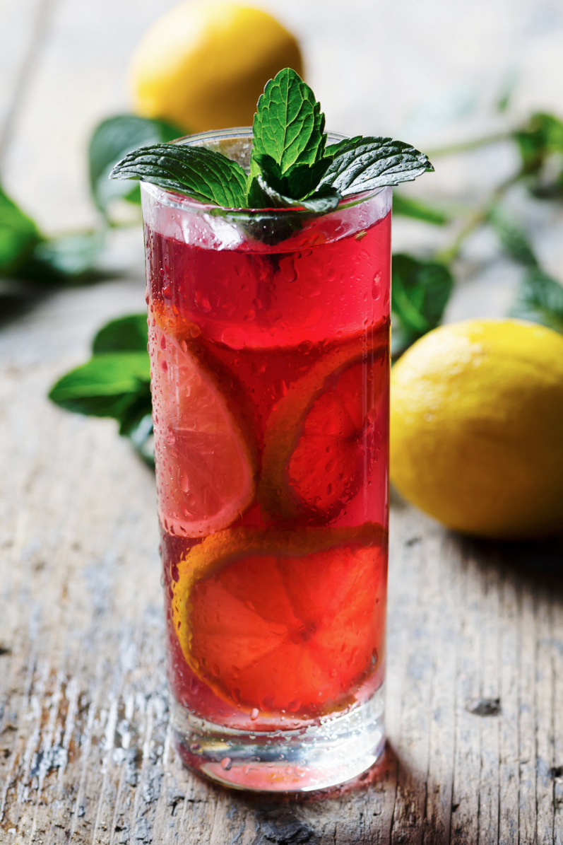 Iced tea with mint leaves and lemons on a wooden background.