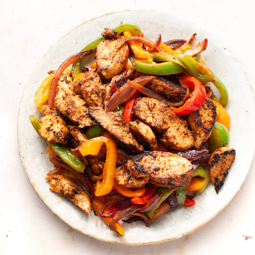 crispy chicken fajitas with bell peppers and onions in a plate