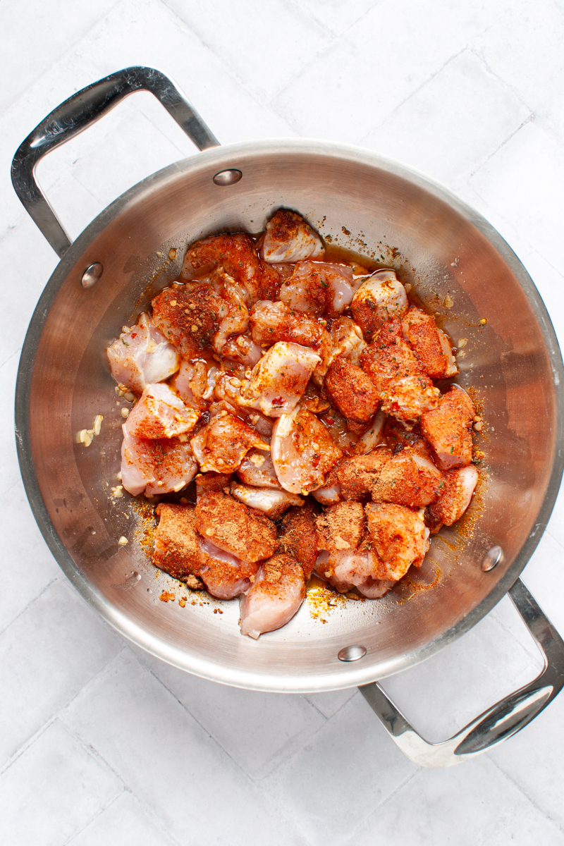 chicken cubes with garlic and seasoning in a wok