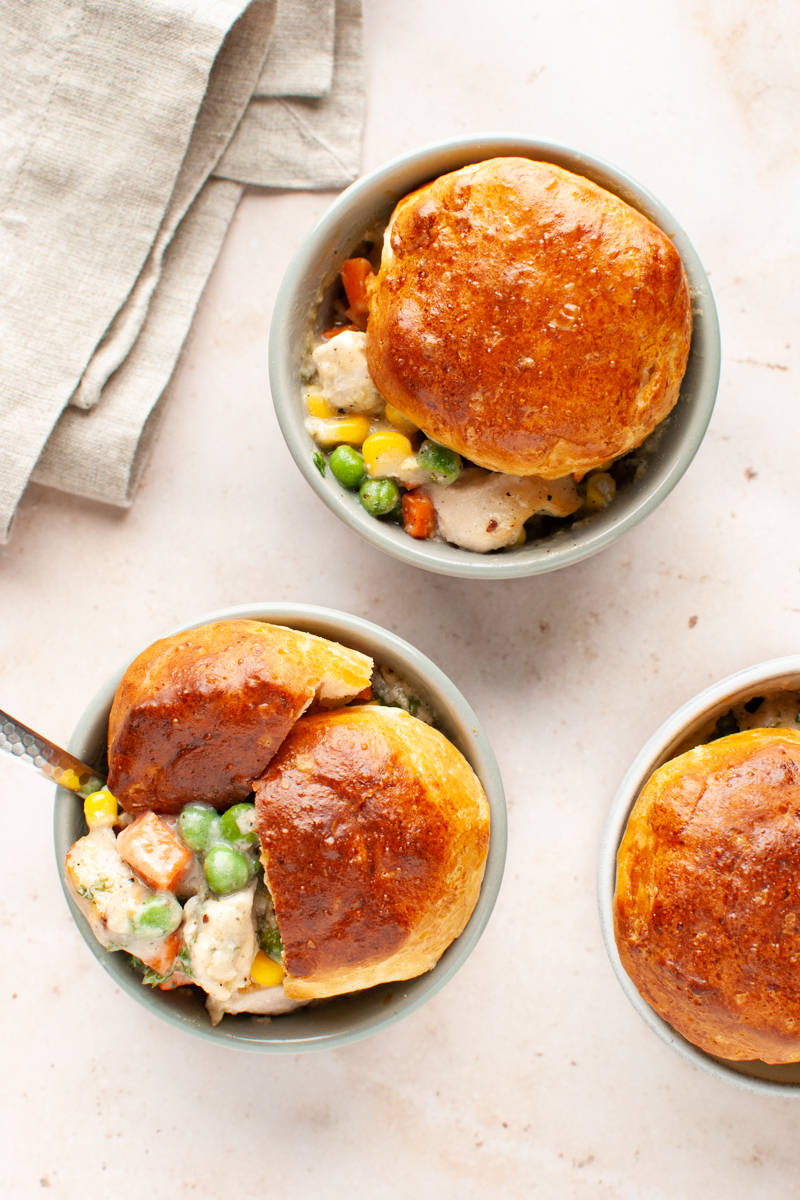 Two ramekins filled with chicken pot pie and topped with biscuits.