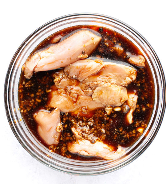 chicken adobo marinating in a glass bowl