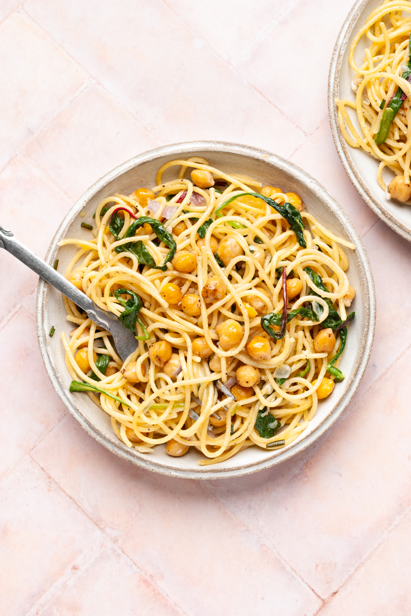 Chickpea pasta with spinach in a plate with fork.