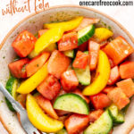 peach watermelon and cucumber salad with sweet basil dressing in a bowl with a fork.