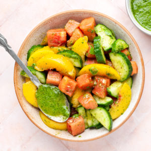 peach and watermelon salad in a bowl with spoon with sweet basil vinaigrette.
