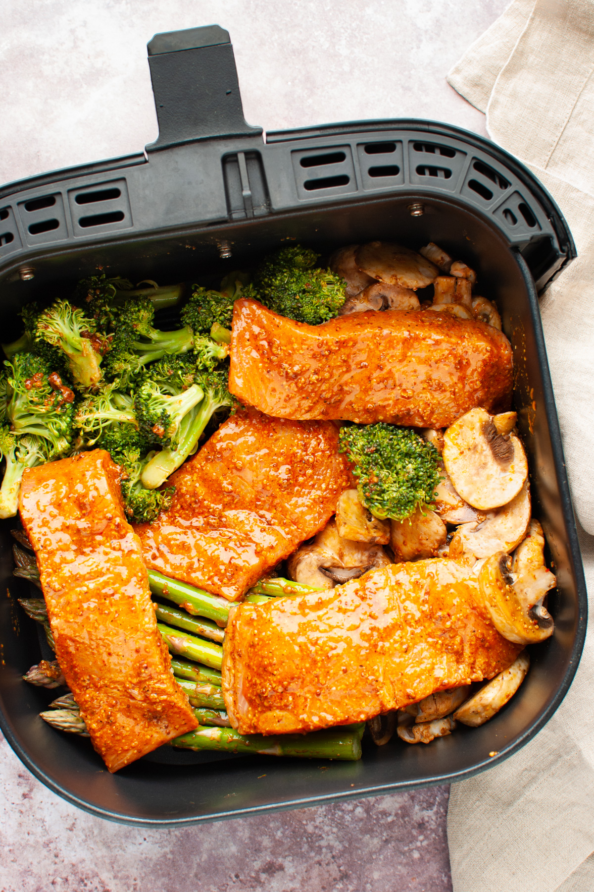 Salmon fillets and vegetables (asparagus, mushrooms, and broccoli in air fryer.