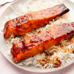 Air fried teriyaki salmon over a bed of rice in a plate.
