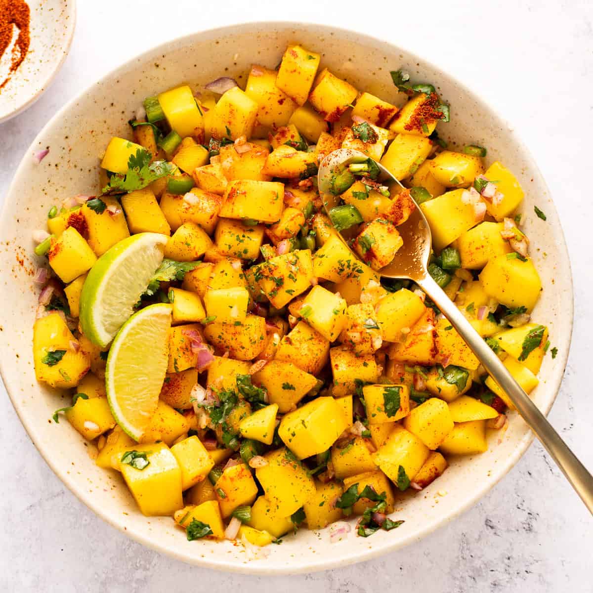 Mango salsa in a bowl with spoon.
