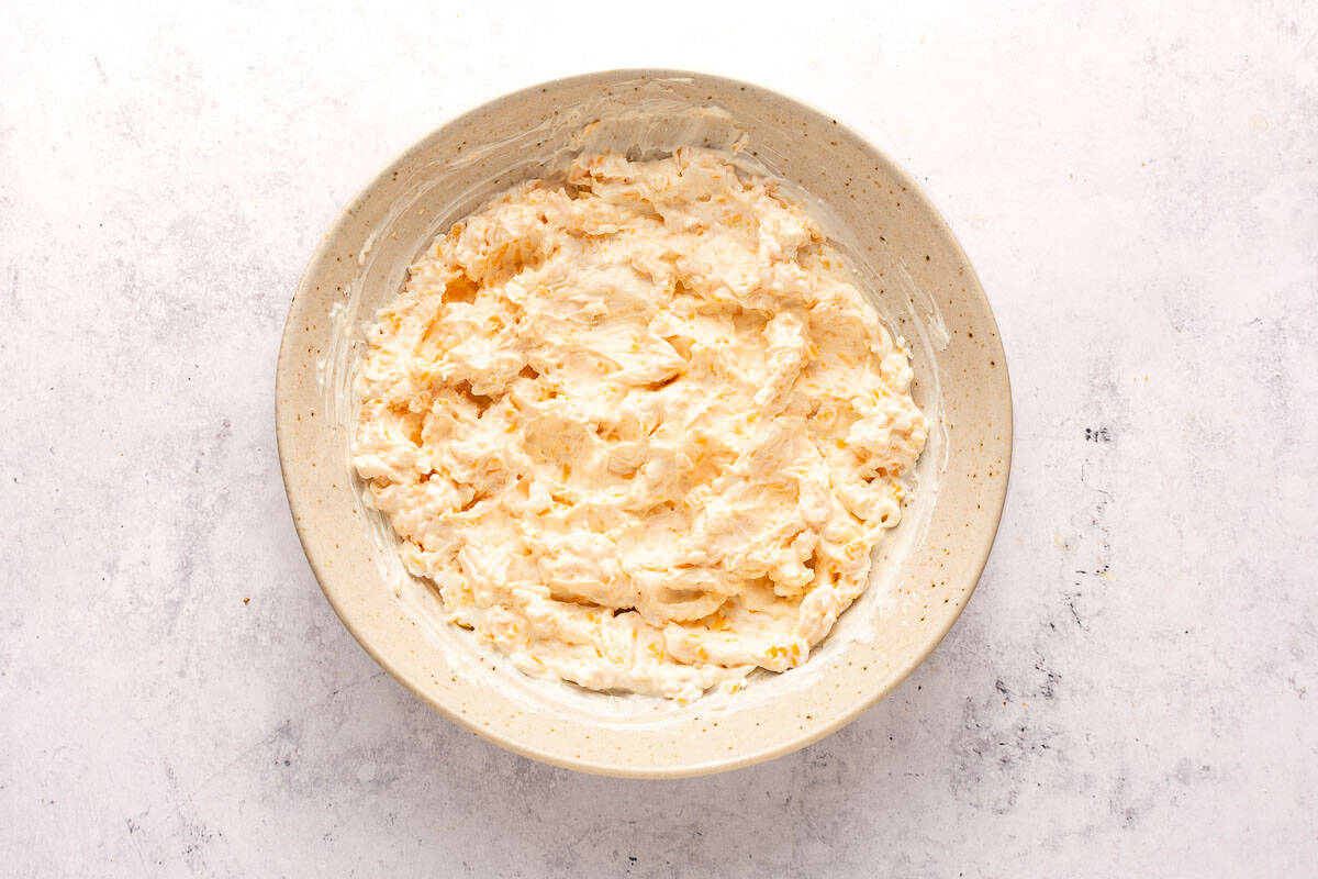 Filling step for mexican pinwheels - cream cheese, cheddar cheese, and sour cream whisked together in a bowl.