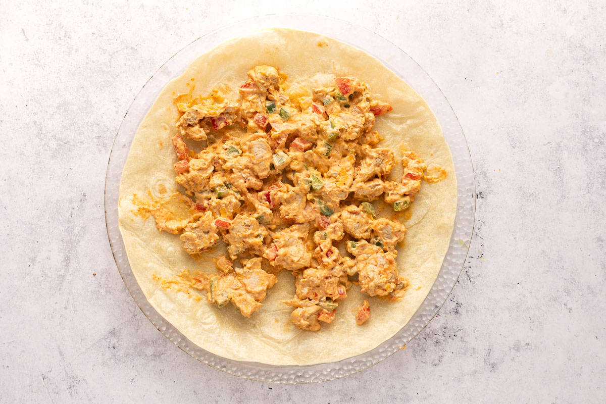 A tortilla spread with the filling for chicken pinwheels.