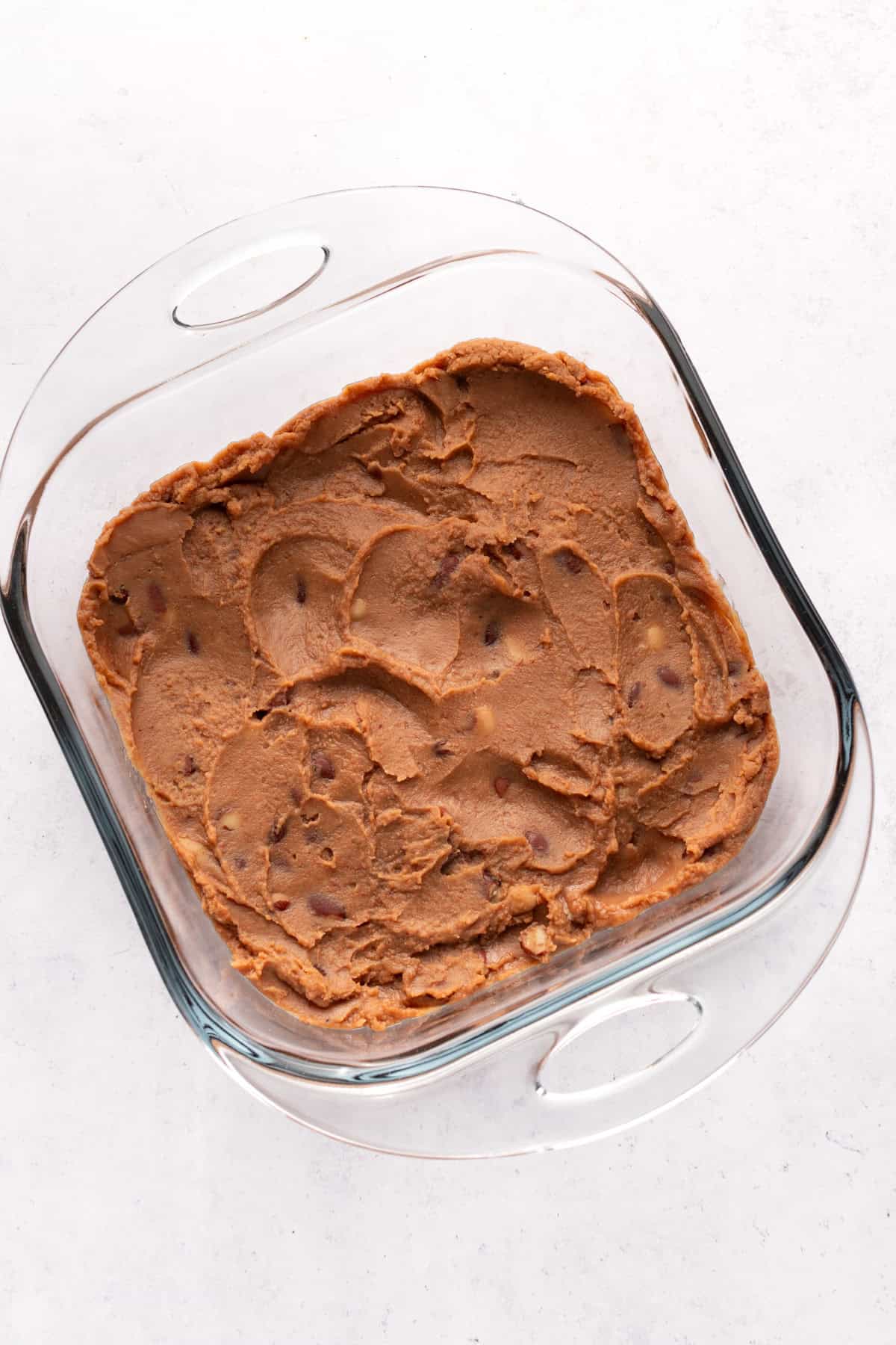 Layer 1 - Refried beans spread in a square Pyrex dish.