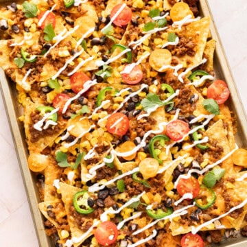 Loaded beef nachos on a sheet pan.