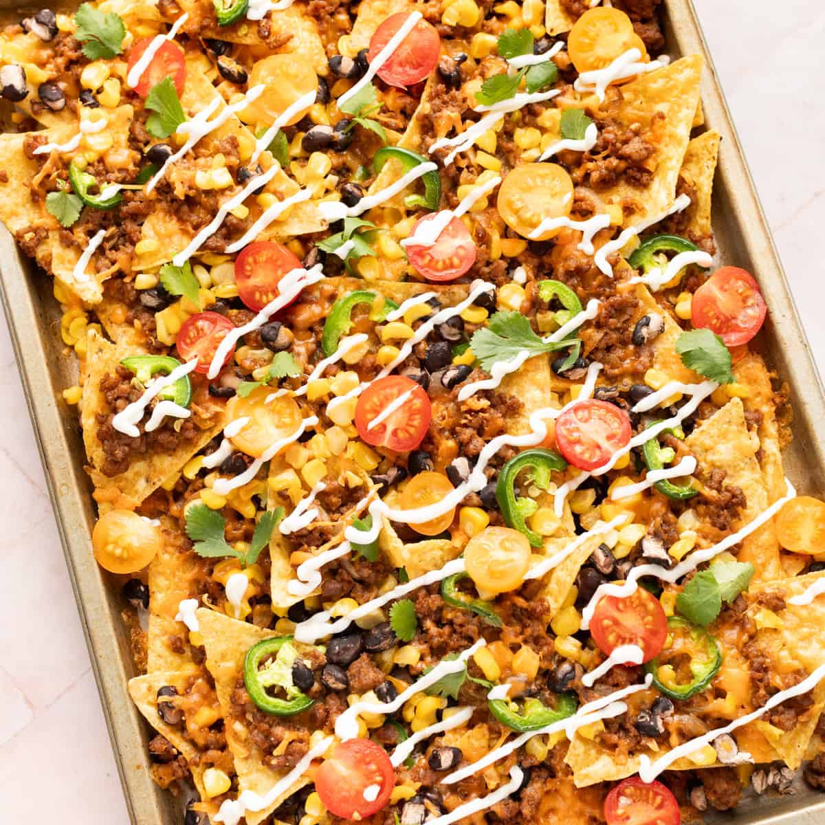Loaded beef nachos on a sheet pan.
