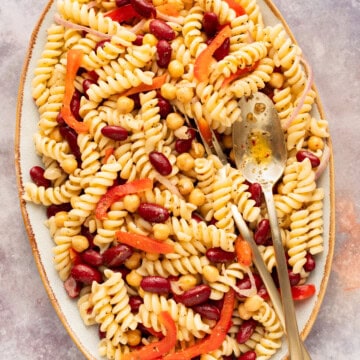 Bean pasta salad in an oval platter with a fork and spoon.