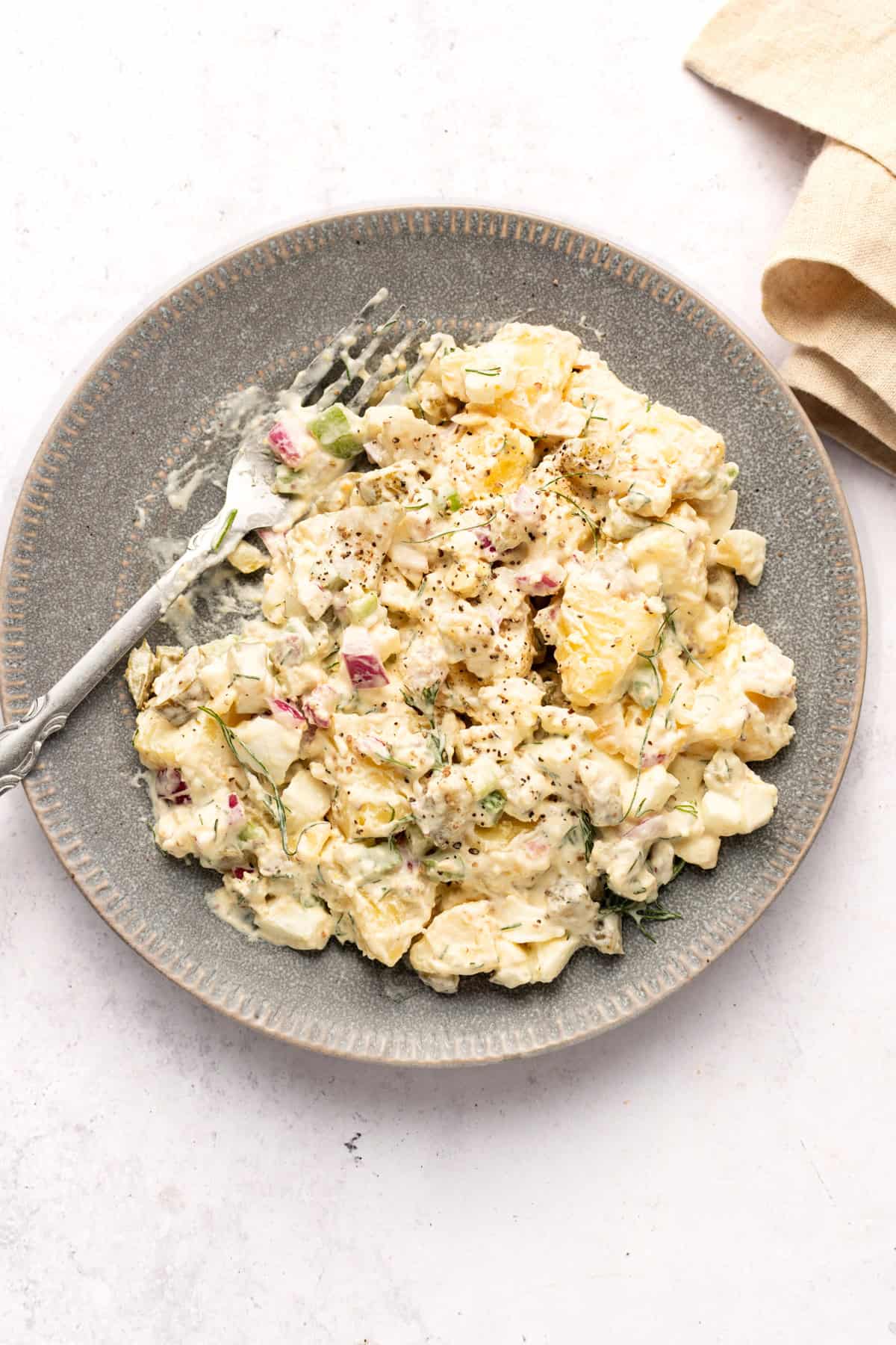 Dill pickle potato salad in plate with a fork.