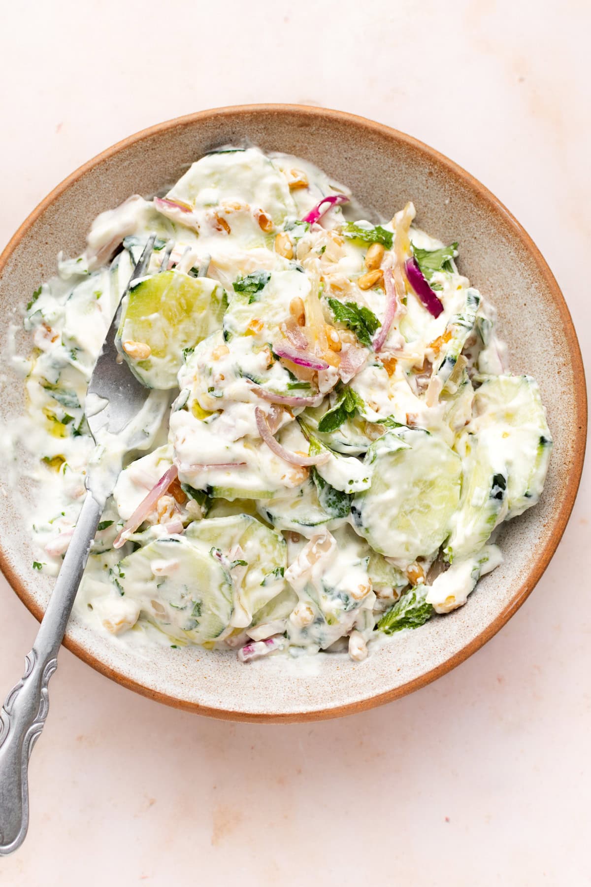 Cucumber salad with greek yogurt dressing in a bowl with fork.